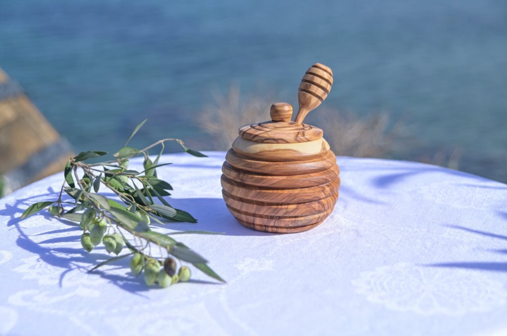 Wooden honey pot with dipper and fresh olives